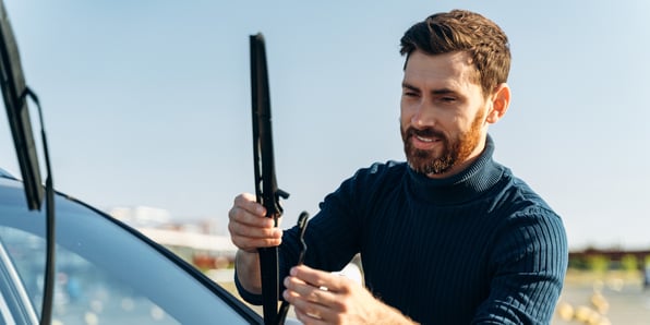 Man adjusts a windshield wiper blade on his vehicle