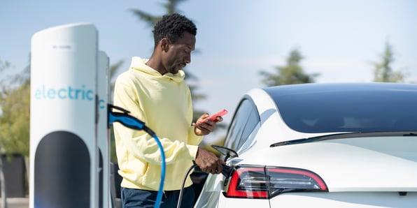 A man plugs in his electric vehicle at a charging station